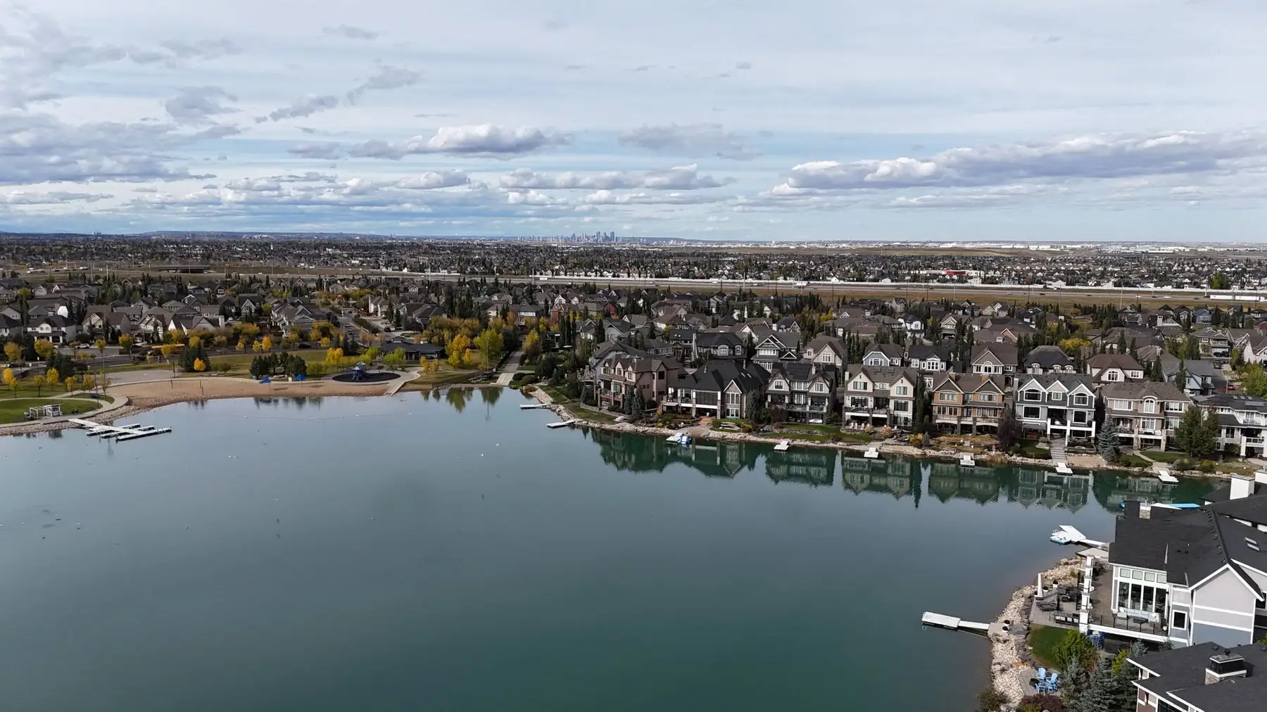 Aerial view of Mahogany Lake, the beach and lake-front homes with downtown Calgary on the horizon