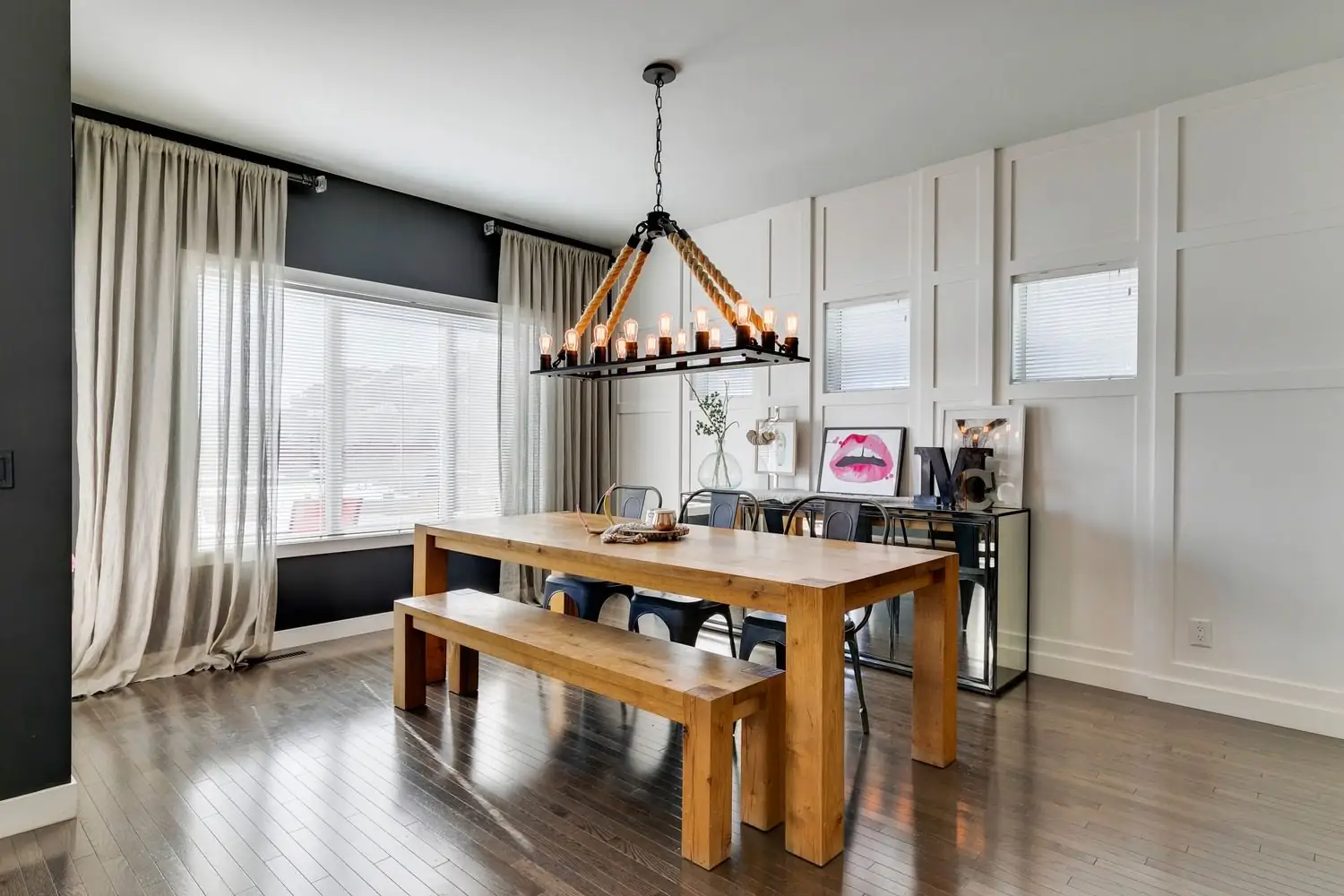 Professionally photographed dining room with a wood table, rope chandelier and panelled feature wall